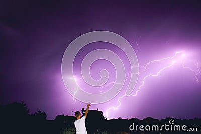 Silhouette of the man of the magician summoning the lightning illuminating the night sky with bright flashes, the riot of the natu Stock Photo