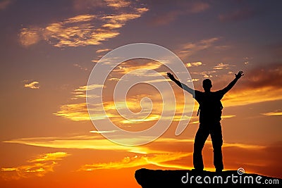 Silhouette of a man on a mountain top on fiery background Stock Photo