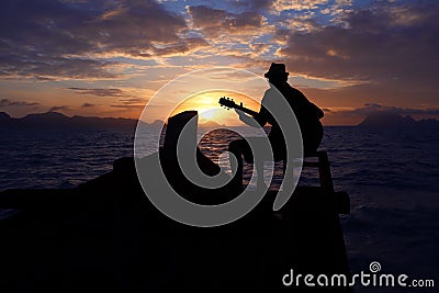 Silhouette man playing a guitar on the boat with blue sky sunrise Stock Photo