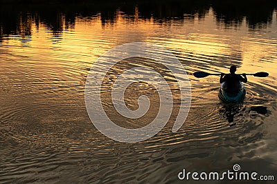 Silhouette of man rowing boat in wave lake water dark natural sunset background Stock Photo