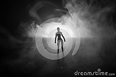 Silhouette of man standing on an dark foggy toned background. Decorated photo with man figure on table with light. Stock Photo