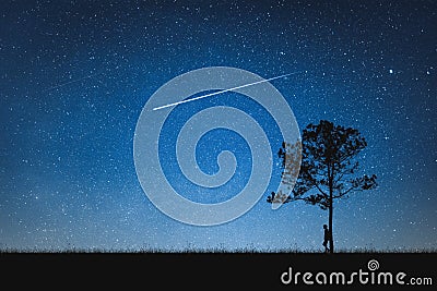 Silhouette of man standing on mountain and night sky with shooting star. Alone concept. Stock Photo