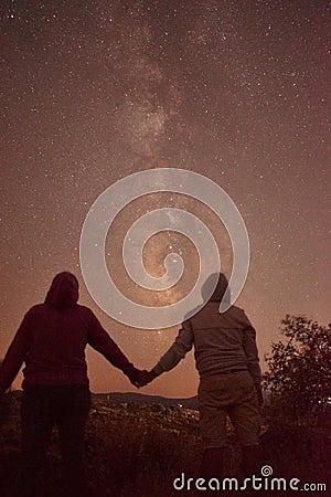 Silhouette of cross at night with beautiful milky way backgroundSilhouette of a man and a woman in love holding hands with beautif Stock Photo