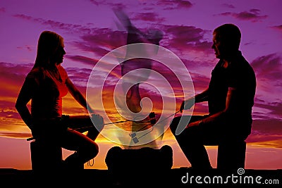 Silhouette man and woman roasting marshmallows Stock Photo