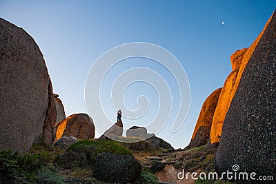 A silhouette of a man and woman stand kissing amongst massive boulders Editorial Stock Photo