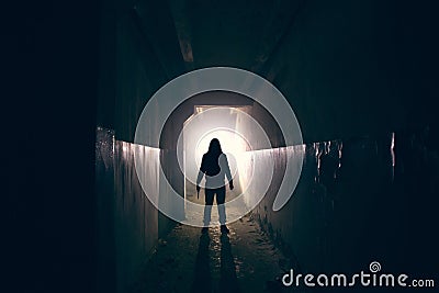 Silhouette of maniac with knife in hand in long dark creepy corridor, horror psycho maniac or serial killer concept Stock Photo