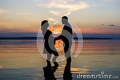 Silhouette of a married couple stands in the water of the lake Stock Photo