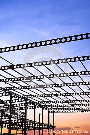 Silhouette of metal castellated beam of factory building structure in construction site against sunset sky background Stock Photo