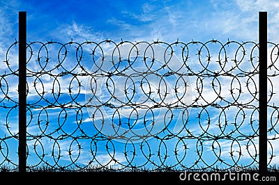 Silhouette of a metal fence with barbed wire Stock Photo