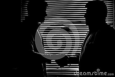 Silhouette in monochrome of two men shaking hands darkness Stock Photo