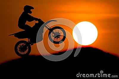 Silhouette of Motorbike rider jump cross slope of mountain with Stock Photo