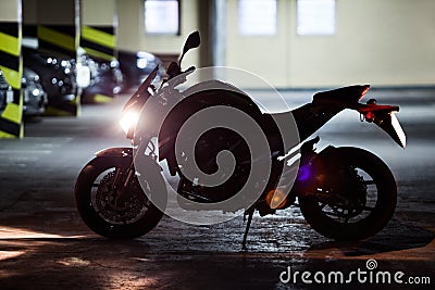 Silhouette of motorcycle standing underground parking with running engine Stock Photo