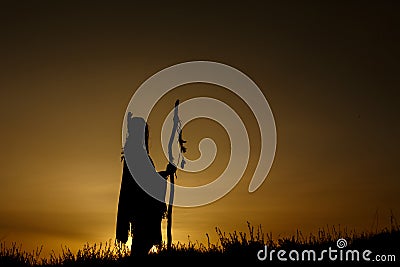 silhouette of native american shaman with pikestaff on background of sunset beutiful in mountains Stock Photo