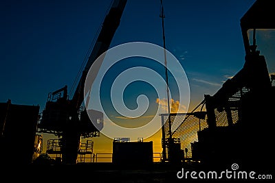 Silhouette of oil and gas wellhead platform and well service worker while working to perforation gas and crude oil reservoir. Stock Photo