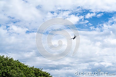 Silhouette of an old four propeller airplane against a backdrop of white clouds and blue sky Stock Photo