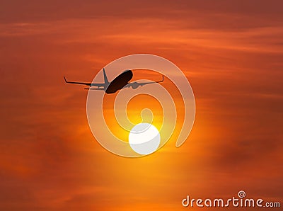 Silhouette passenger airplane flying above the sun during sunset Stock Photo