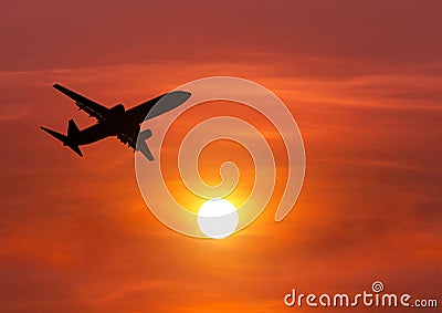 Silhouette passenger airplane flying above the sun during sunset Stock Photo