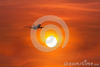 Silhouette passenger airplane flying away in to sky high altitude above the sun during sunset time Stock Photo