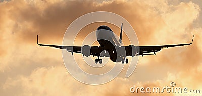 Silhouette passenger airplane. Front of silhouette airplane is flying in the orange sky with clouds Stock Photo