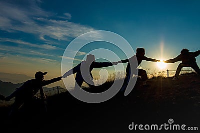 Silhouette of people helping each other hand by hand Editorial Stock Photo