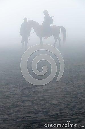 Silhouette of people and horses in fog or mist Stock Photo