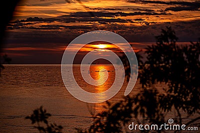 Silhouette of people on SUP boards on horizon of sea at orange sunrise. Active hobby on the water Stock Photo