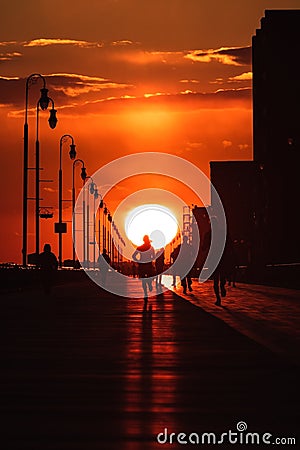 Silhouette of a person running on a boardwalk at sunset. Long Beach NY Editorial Stock Photo