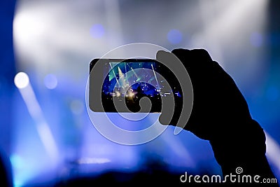 Silhouette of a person shooting the concert stage with smart phone Stock Photo