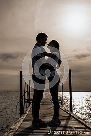 Silhouette photo of romantic couple enjoying sunset harbor view Stock Photo