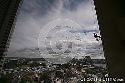 Silhouette picture of construction rope access worker wearing a hard hat, full body safety harness working at height, abseiling Stock Photo