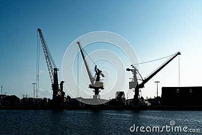 Silhouette of port cranes in a large commercial port under a blue evening sky at twilight Editorial Stock Photo