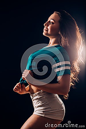 Silhouette portrait of a beautiful brunette woman sideways. girl in white shorts and t-shirt smiles and closes her eyes. Slim Stock Photo