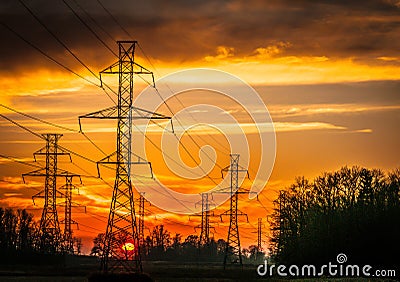 Silhouette of power grid against a dramatic sunset sky Stock Photo