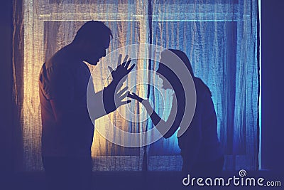 Silhouette of quarreling man and woman at the night window. Married couple husband and wife, violence in evening light of home Stock Photo