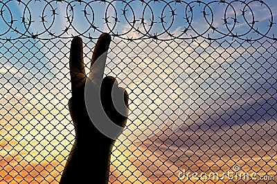 Silhouette refugee arms near the border fence Stock Photo