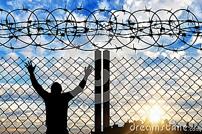 Silhouette of a refugee near the fence Stock Photo