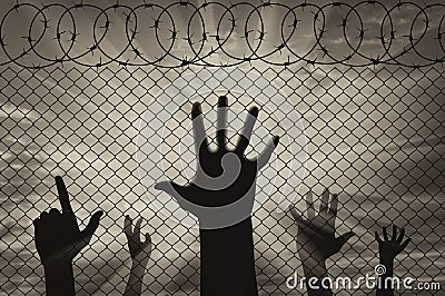 Silhouette refugees hands near the border fence Stock Photo