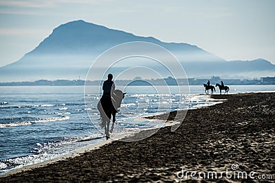 Silhouette of Riders at the beach riding horses Stock Photo