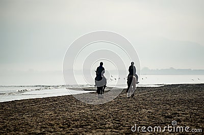 Silhouette of Riders at the beach riding horses Stock Photo