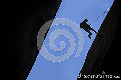 Silhouette of rock climber rappelling Stock Photo