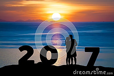 Silhouette of romantic a couple hug kissing against summer sea in sunset twilight sky while celebrating happy new year 2017 Stock Photo