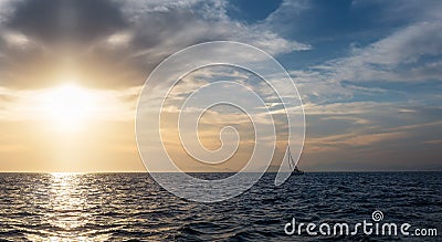 Silhouette Sail boat gliding in open sea at sunset. Tilted monohull in the evening Stock Photo