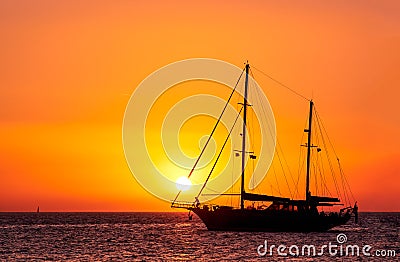 Silhouette of sailing boat with sails down against sun at sunset, sun glare on sea waters. Romantic seascape, sun touch Stock Photo