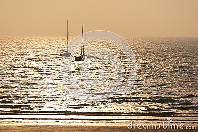 Silhouette of sailing boats at sunset on a beach in PlÃ©neuf, CÃ´tes d`Armor, Britanny France Stock Photo