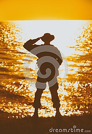 Silhouette of saluting on shore commando solder Stock Photo