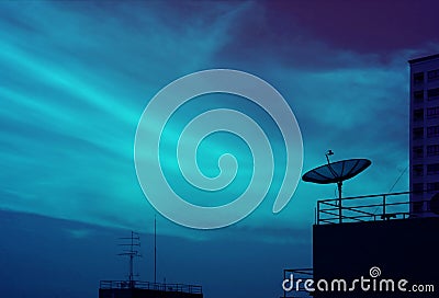 Silhouette of Satellite Dish on the High Building Against Evening Sky in Blue Color Tone Stock Photo