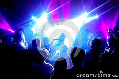 Silhouette of a saxophonist surrounded by a lot of people under the spotlights and neon lights Editorial Stock Photo