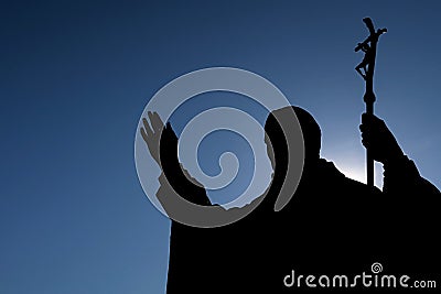 Silhouette of sculpture of pope John Paul The Second, with sun shining from behing him. Stock Photo