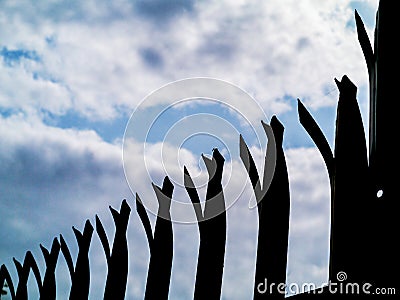 Silhouette of a security anti climbing fence. Dramatic blue cloudy sky. Concept safety, defense, private property protection Stock Photo