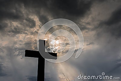 Silhouette of a simple catholic cross, dramatic stormclouds after heavy rain Stock Photo